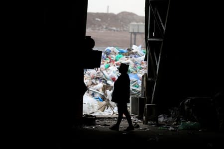 A waste picker walks past a garbage dump at the state entity CEAMSE in the neighborhood of Jose Leon Suarez, on the outskirts of Buenos Aires