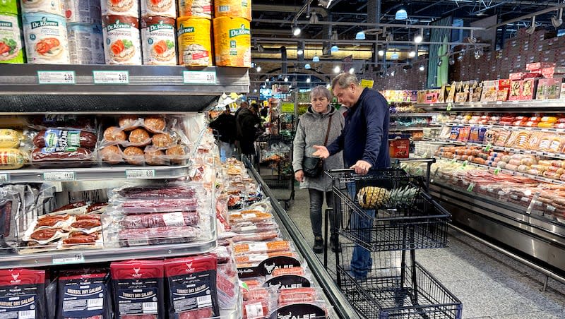 Customers check prices while shopping at a grocery store in Wheeling, Ill., Saturday, Jan. 27, 2024.
