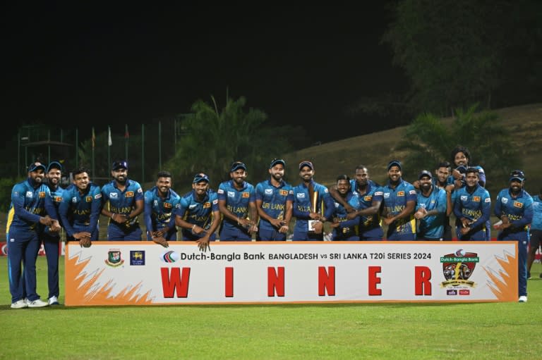 Sri Lanka's cricketers pose with the Twenty20 trophy after winning the three-match series against Bangladesh 2-1 -- pointing to their watches in an apparent reference to the "timed out" controversy of last year's World Cup (MUNIR UZ ZAMAN)