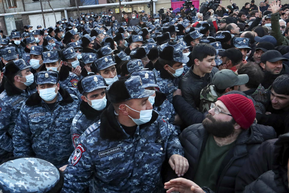 Police wearing face masks to protect against coronavirus, block opposition demonstrators during a rally to pressure Armenian Prime Minister Nikol Pashinyan to resign in Yerevan, Armenia, Tuesday, March 9, 2021. Thousands of opposition supporters blockaded the Armenian parliament building and engaged in occasional scuffles with police on Tuesday to press a demand for the country's prime minister to step down. (Stepan Poghosyan/PHOTOLURE via AP)