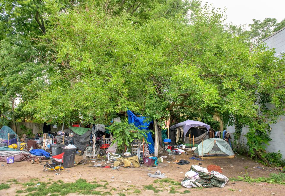 Tents and makeshift shelters sit under cover of tree branches at a homeless encampment off Knoxville Avenue in Peoria.