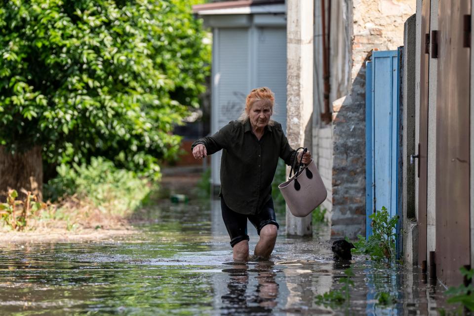 A resident wades through water after a dam burst in Kherson (AP)