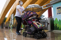 A man and a child wearing masks to curb the spread of the new coronavirus visit a local park in Beijing on Saturday, May 23, 2020. New coronavirus cases dropped to zero in China for the first time Saturday but overwhelmed hospitals across Latin America – both in countries lax about lockdowns and those lauded for firm, early confinement. (AP Photo/Ng Han Guan)