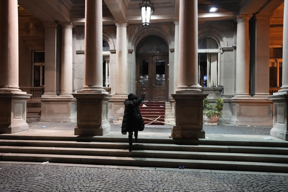 A protester approaches entrance of the city council building secured by anti-riot police in Belgrade, Serbia, Sunday, Dec. 24, 2023. Police in Serbia have fired tear gas to prevent hundreds of opposition supporters from entering the capital's city council building to protest what election observers said were widespread vote irregularities during a general election a week ago. (AP Photo/Darko Vojinovic)