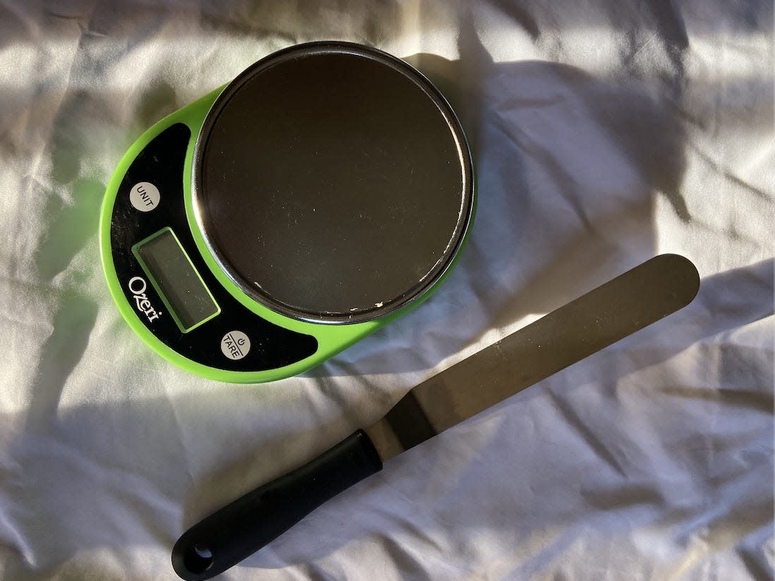 Green food scale and offset spatula on white sheet