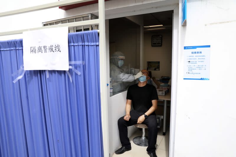 Medical staff member collects a swab from a man for nucleic acid test at China-Japan Friendship Hospital in Beijing