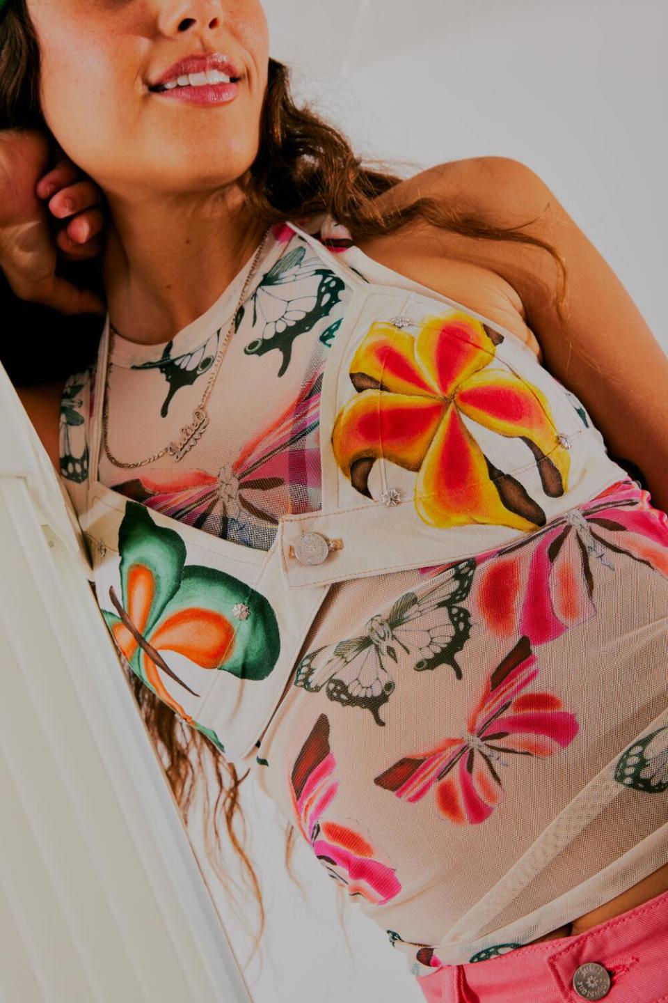 A close-up image of a woman wearing a top painted with butterflies.