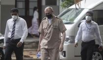 Sri Lankan police officers escort Russian Captain Tyutkalo Vitaly, center, of fire damaged container ship MV X-Press Pearl at a court before the hearing begins in Colombo, Sri Lanka. Monday, June 14, 2021. (AP Photo/Eranga Jayawardena)