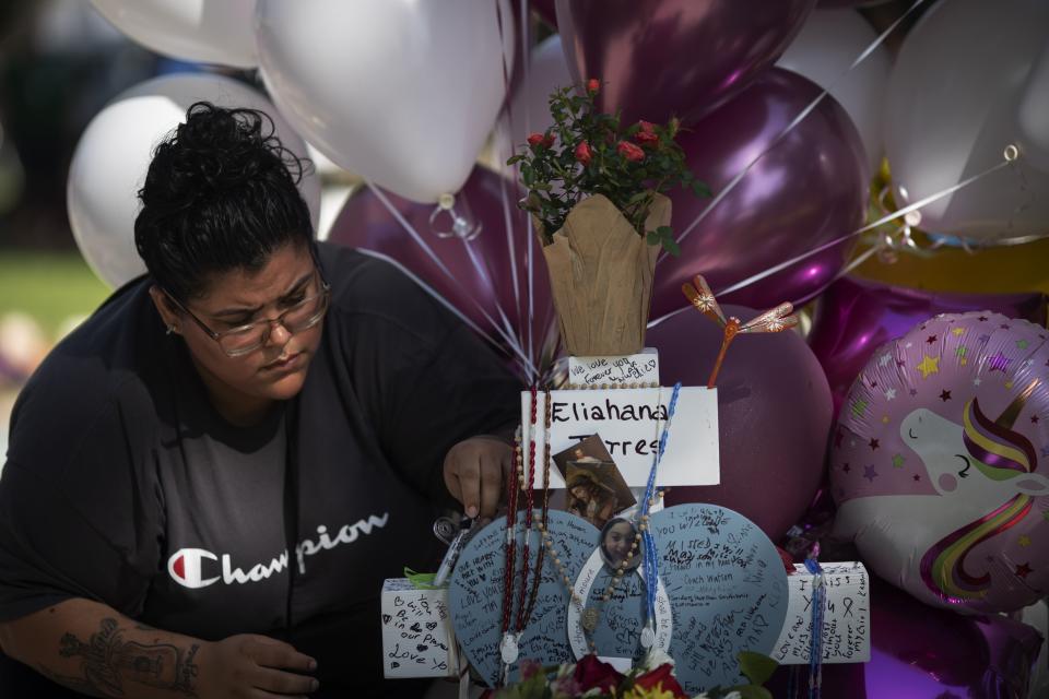 CORRECTS SPELLING OF FIRST NAME TO ELIAHNA, NOT ELIAHANA - McKenzie Hinojosa, 28, writes a message on a cross for her cousin Eliahna Torres, at a memorial site for victims, including her cousin, killed in the Robb Elementary school shooting, Saturday, May 28, 2022, in Uvalde, Texas. (AP Photo/Wong Maye-E)