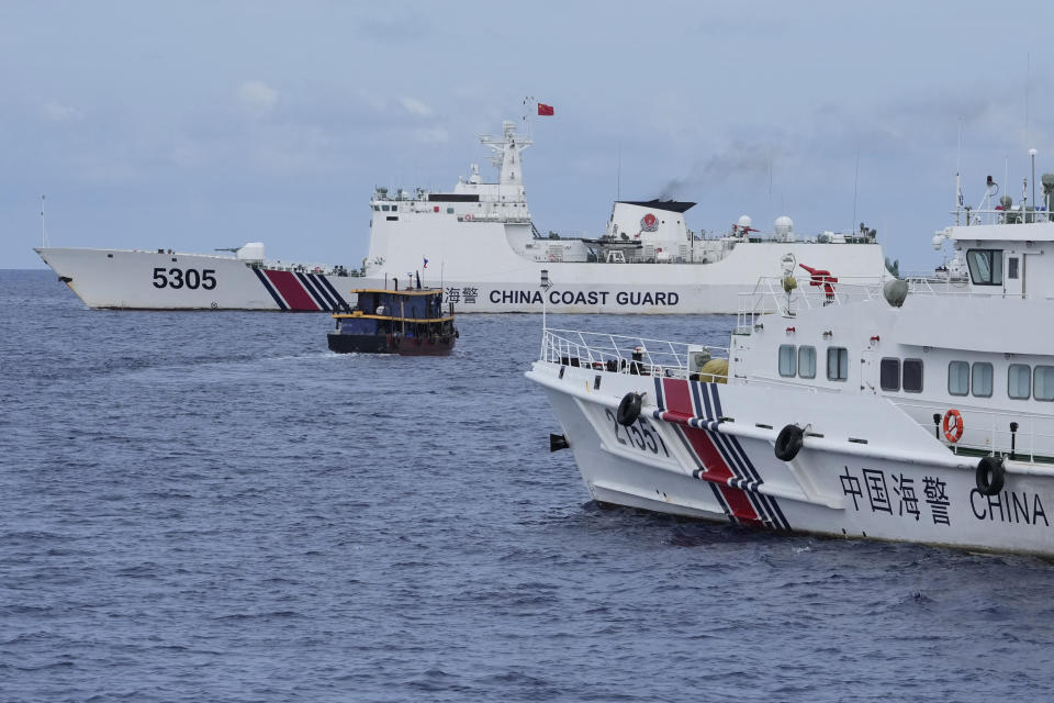 FILE - A Philippine supply boat, center, maneuvers around Chinese coast guard ships as they try to block its way near Second Thomas Shoal, locally known as Ayungin Shoal, at the disputed South China Sea on Aug. 22, 2023. Two Philippine supply boats breached a Chinese coast guard blockade in the South China Sea on Wednesday, Oct. 4, in a recurring confrontation near the disputed shoal some fear could spark a larger security crisis that could draw in the United States. (AP Photo/Aaron Favila, File)