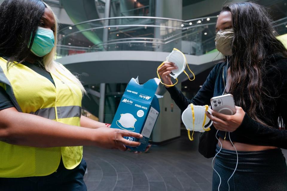 An MTA employee hands out masks outside a subway station (AP)