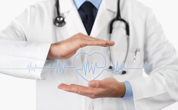 Doctor holding hands over hearbeat monitor icon