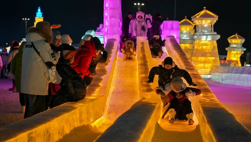 Visitors enjoy an ice slide as they visit the annual Harbin Ice and Snow World in Harbin in northeastern China's Heilongjiang Province, Monday, Jan. 8, 2024.