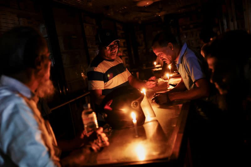 A pharmaceutical shop uses candle lights to serve customers during countrywide blackout in Dhaka