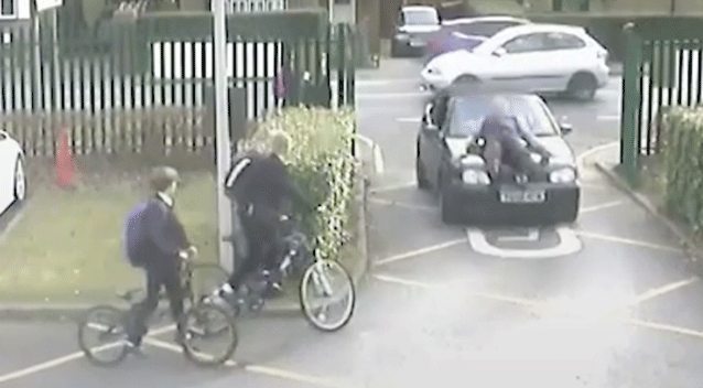 The teacher is mounted on the parent's car as it accelerates through the school grounds. Source: Press Association