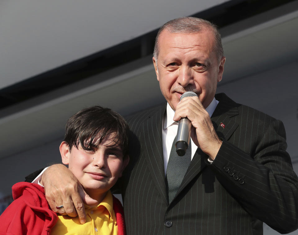 Turkey's President Recep Tayyip Erdogan reacts with a young boy as he addresses the supporters of his ruling Justice and Development Party during a rally in Kocaeli, Turkey, Tuesday, March 19, 2019. Ignoring widespread criticism, Erdogan on Tuesday again showed excerpts of a video taken by the attacker who killed 50 people in mosques in New Zealand, to denounce rising hatred and prejudice against Islam. (Presidential Press Service via AP, Pool)
