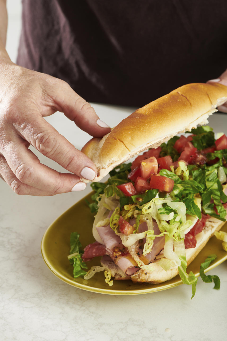 This May 2022 photo shows a submarine sandwich being prepared in New York. The overstuffed sandwich on a roll has layers of meats, cheese, condiments and so on. (Cheyenne Cohen via AP)