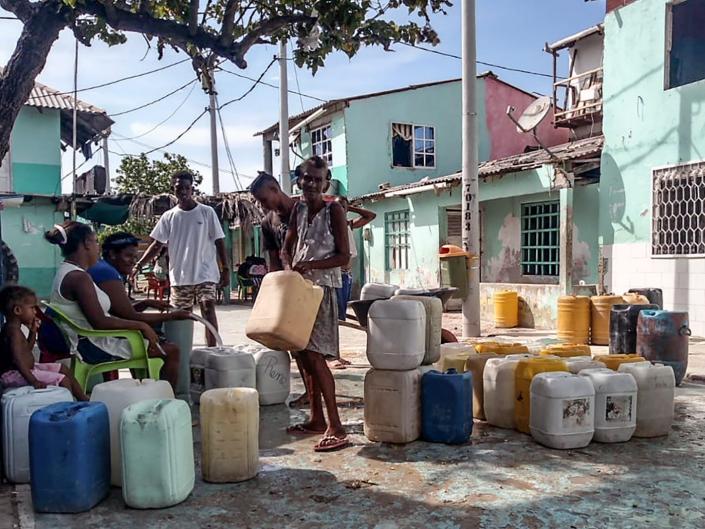 Inhabitants carry buckets of water in a street at Santa Cruz del Islote island, located in the Colombian Caribbean, off the coast of Sucre Department, on June 17, 2020.