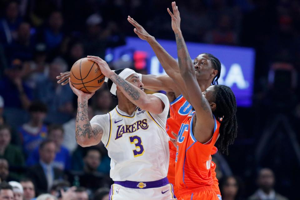 Thunder forward Jalen Williams, center, and guard Cason Wallace, right, defend Lakers forward Anthony Davis during Saturday's game at Paycom Center.