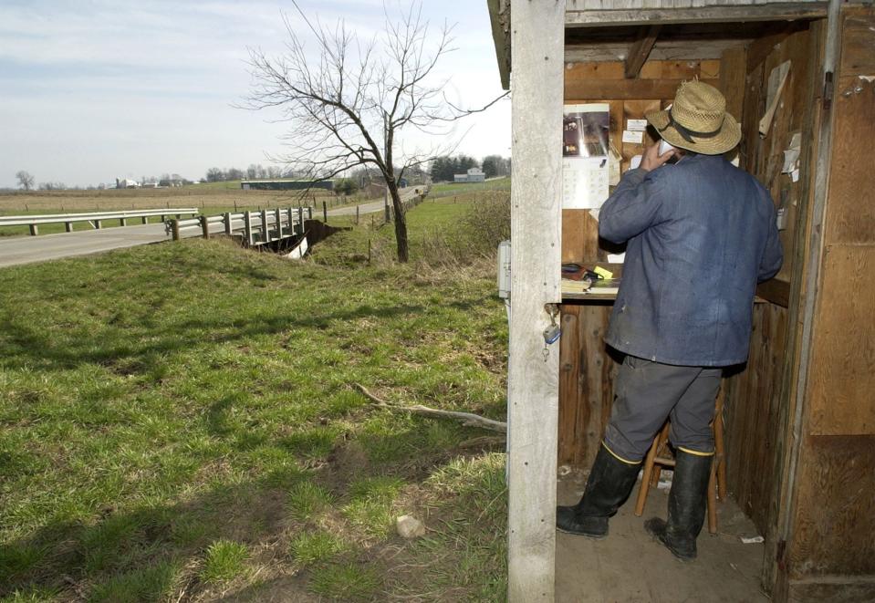 An Amish man uses a phone on a desolate road April 7, 2004, in Mt. Hope, Ohio.