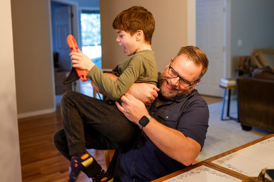 Nate Bearinger shares a laugh with his son Elliot, 8, after he finish math homework at their home in New Boston on Friday, Oct. 20, 2023.