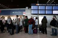 People line up at the Delta Air Lines ticketing desk inside Terminal 2E at Paris Charles de Gaulle airport