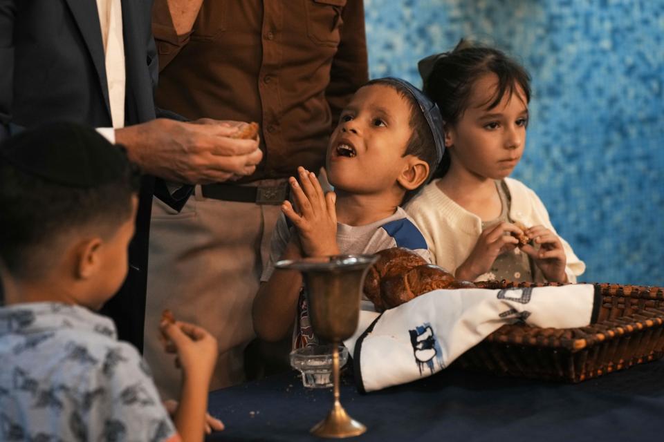 Niños judíos comen trozos de pan challah después de que se recitó una oración durante un servicio por el Sabbat en la sinagoga Beth Shalom, el viernes 16 de febrero de 2024, en La Habana, Cuba. Se cree que los judíos llegaron a Cuba junto con Cristóbal Colón en 1492, pero la comunidad cubana de esta religión comenzó oficialmente en la primera etapa del siglo XX, dijo el vicepresidente de la comunidad hebrea en la isla. (AP Foto/Ramón Espinosa)