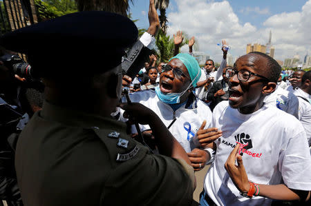 Kenyan doctors speak to a policeman attempting to disperse them during a strike to demand fulfilment of a 2013 agreement between their union and the government that would raise their pay and improve working conditions outside Ministry of Health headquarters in Nairobi, Kenya December 5, 2016. REUTERS/Thomas Mukoya
