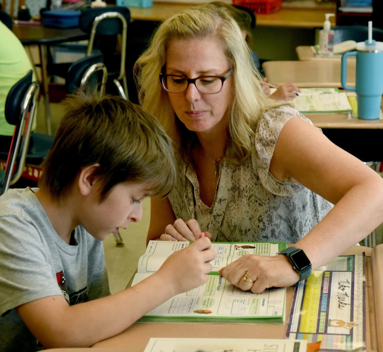 Mason Central fourth grade teacher Jill Bennett helps Niko Marks with his math book during class. 