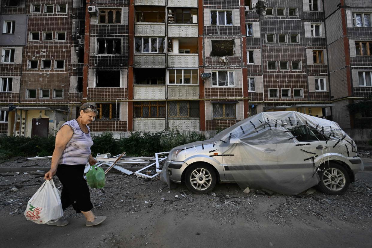 A woman gathers her belongings from a heavily damaged residential building in Saltivka, a northern district of the second largest Ukrainian city of Kharkiv on July 31, 2022, amid the Russian invasion of Ukraine.