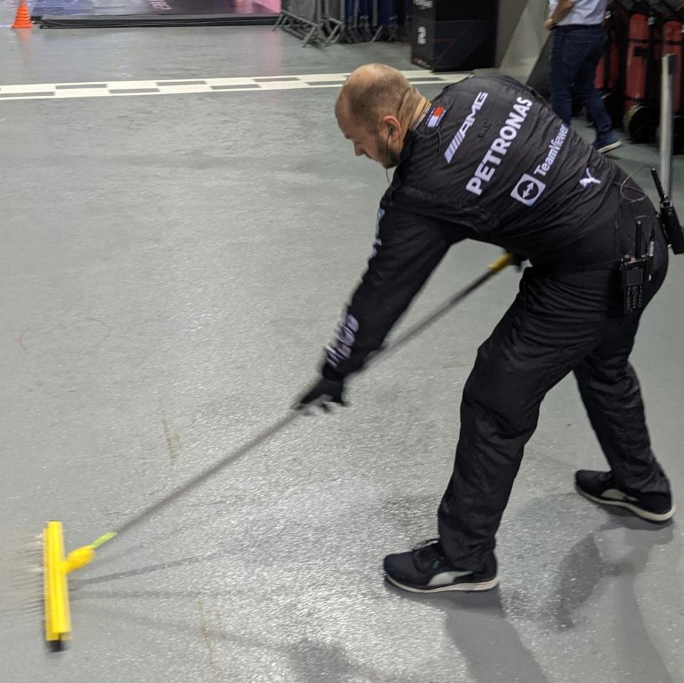 A mechanic sweeps the damp from outside George Russell's garage