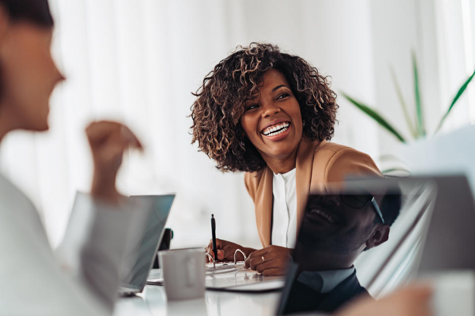 Portrait of cheerful african american businesswoman discussing and smiling at the meeting with colleagues