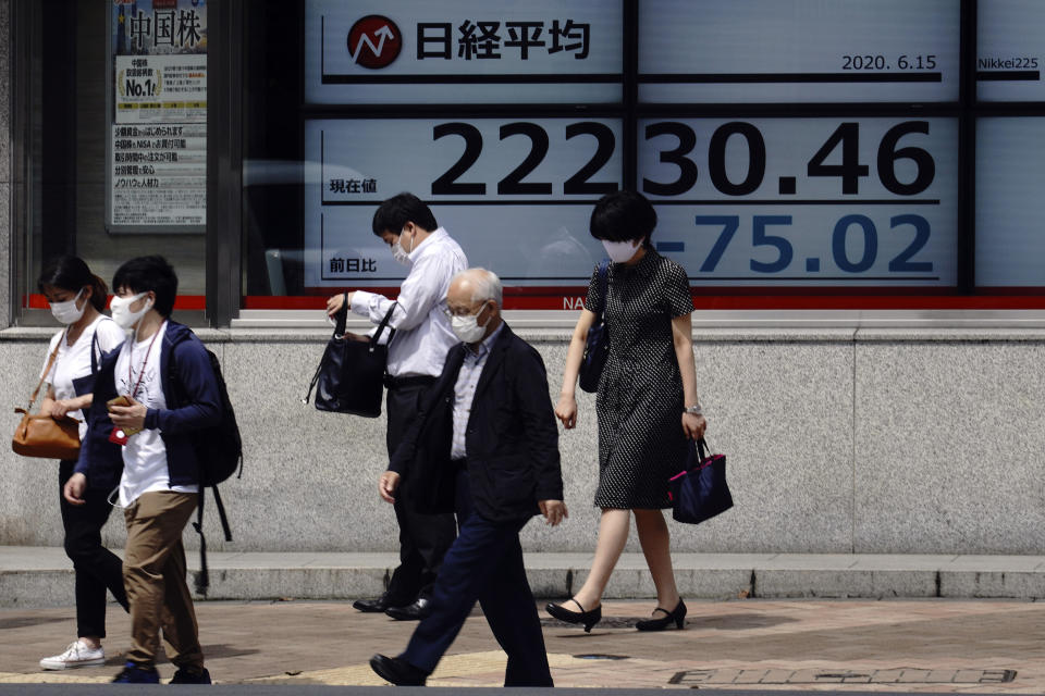 People walk past an electronic stock board showing Japan's Nikkei 225 index at a securities firm in Tokyo Monday, June 15, 2020. Asian shares were mostly lower Monday on concern over a resurgence of coronavirus cases and pessimism after Wall Street posted its worst week in nearly three months. (AP Photo/Eugene Hoshiko)