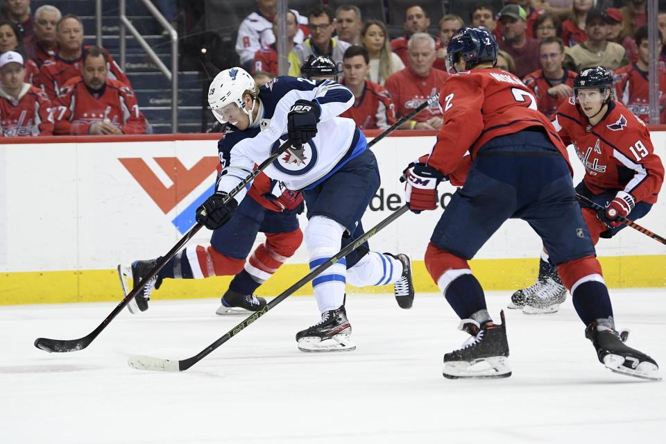 Winnipeg Jets right wing Patrik Laine (29), of Finland, shoots the puck against Washington Capitals defenseman Matt Niskanen (2) and center Nicklas Backstrom (19) during the second period of an NHL hockey game, Sunday, March 10, 2019, in Washington. (AP Photo/Nick Wass)