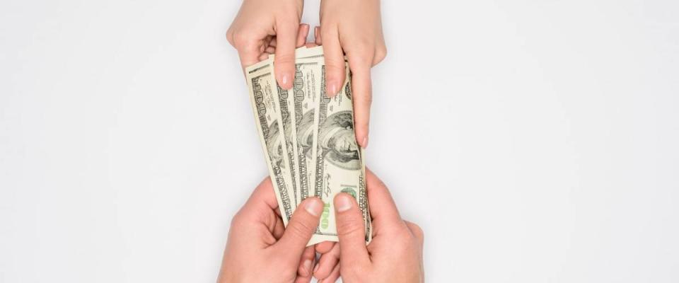 partial view of couple sharing dollar banknotes isolated on grey