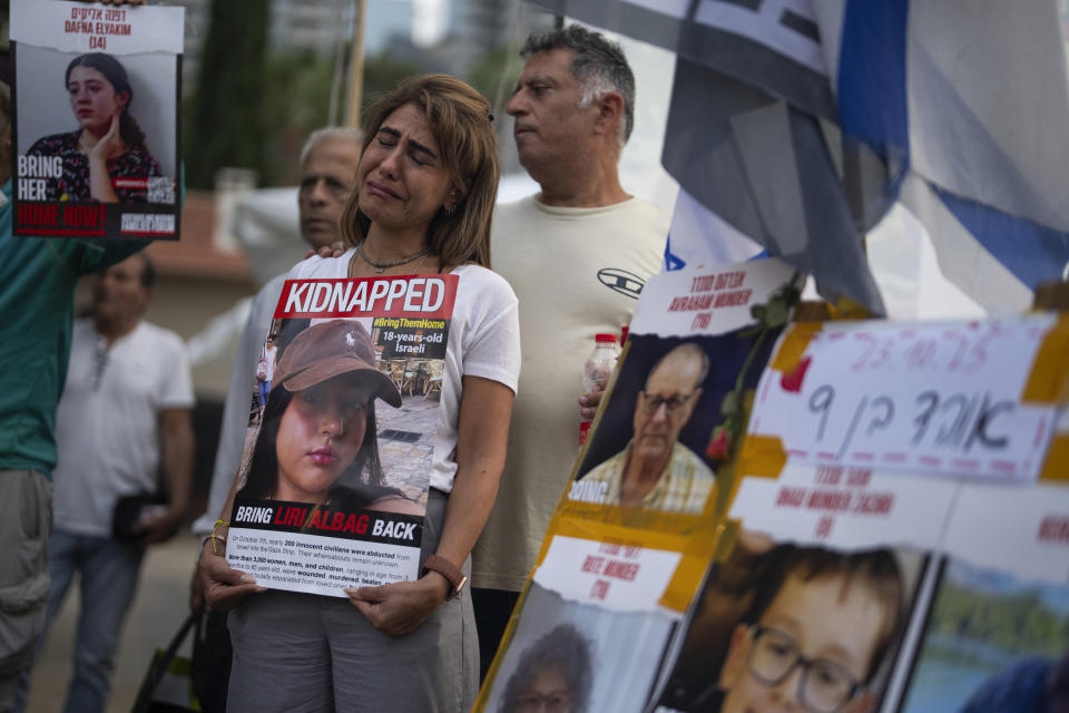 An Israeli woman cries as she holds a photo of a woman who was kidnapped, during a rally calling for the return of more than 200 people captured by Hamas militants, in Tel Aviv, Israel, Monday, Oct. 23, 2023. On Oct. 7, the militant Hamas rulers of the Gaza strip carried out an unprecedented, multi-front attack that killed over 1,400 and captured more than 200. (AP Photo/Petros Giannakouris)