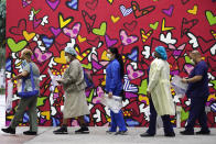 FILE - In this Sept. 22, 2020, file photo, healthcare workers line up for free personal protective equipment in front of a mural by artist Romero Britto at Jackson Memorial Hospital in Miami. The pandemic began with devastation in the New York City area, and was followed by a summertime crisis in the Sun Belt. But it is now striking cities with much smaller populations, often in conservative corners of America where anti-mask sentiment runs high, creating problems at hospitals and schools in the Midwest and West. (AP Photo/Wilfredo Lee)