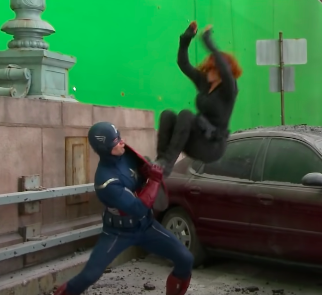 Heidi in the same costume, doing a stunt on wires in front of a green screen