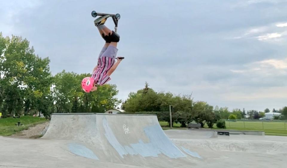 Dex Foster hangs upside down in the air halfway through a backflip at Carstairs skatepark.