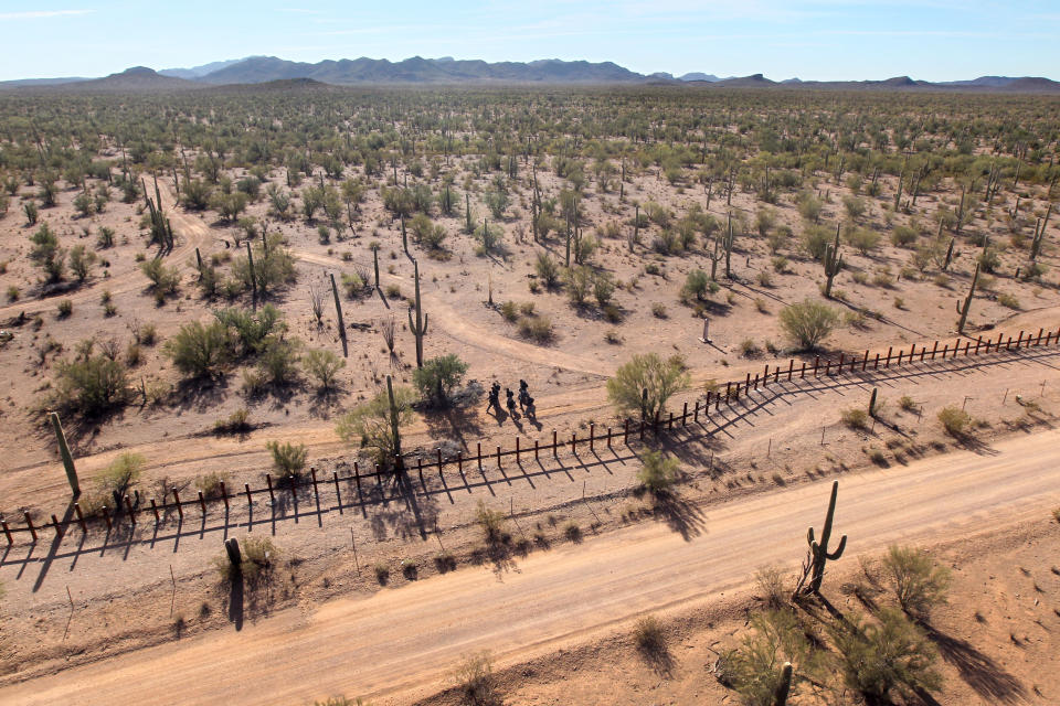 <p>A group of young men walk along the Mexican side of the U.S.-Mexico border fence in a remote area of the Sonoran Desert on Dec. 9, 2010, in the Tohono O’odham Reservation, Ariz. Federal agents flying over the group said the men would probably cross the fence after dark to make an illegal trek into the United States. (Photo: John Moore/Getty Images) </p>