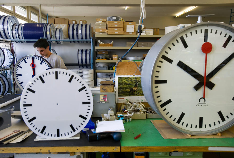 FILE - In this Sept. 21, 2005 file photo, an employee at Mobatime Swiss Inc. finishes a Swiss railway station clock at their factory in Sumiswald, Switzerland. Switzerland's national rail company is accusing Apple Inc. of stealing the iconic look of its station clocks for the iOS 6 operating system used on iPad mobile devices. (AP Photo/Keystone, Martin Ruetschi, File)