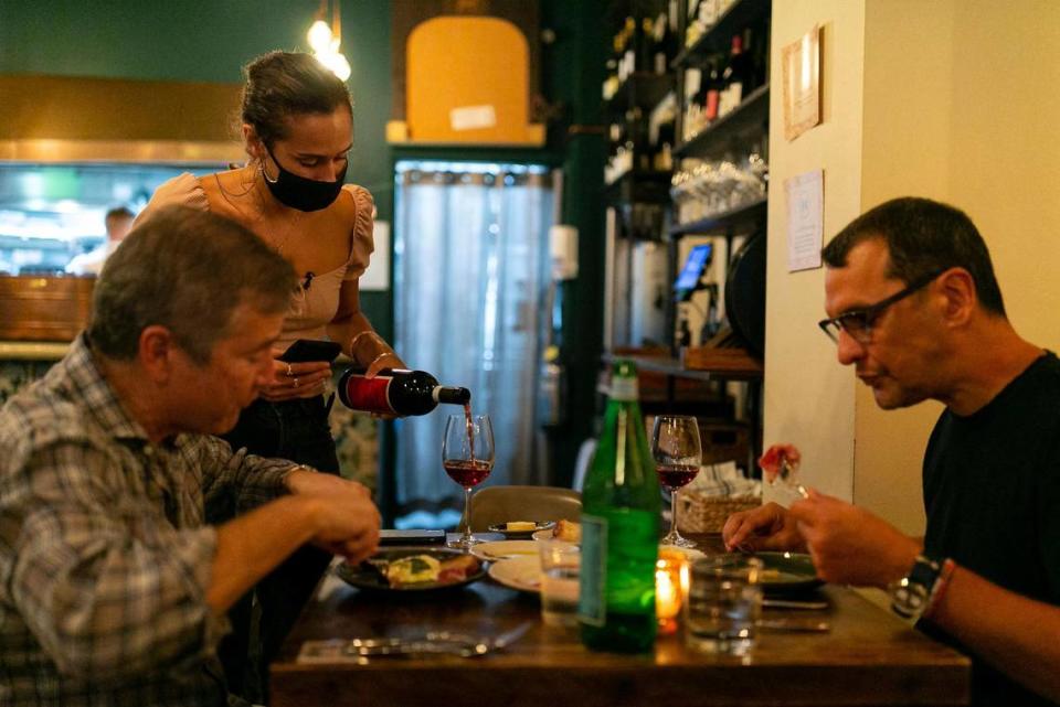 Lina Goujjane, 30, serves wine to Louis Vigden, left and Alvaro Perez Miranda during the opening day of her pop-up, Da Lida, which operates at the French-Persian restaurant Fooq’s in downtown Miami.