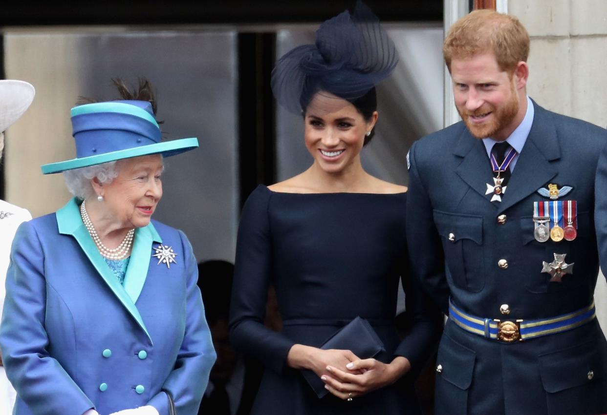 Queen Elizabeth II, left, Meghan, Duchess of Sussex; and Prince Harry, Duke of Sussex watch the RAF flypast on the balcony of Buckingham Palace as members of the Royal Family attend events to mark the centenary of the RAF on July 10, 2018 in London, England.