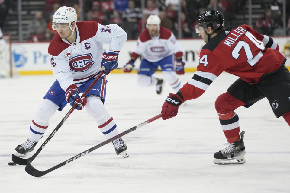 Montreal Canadiens center Nick Suzuki (14) skates with the puck as New Jersey Devils defenseman Colin Miller (24) moves in during the first period of an NHL hockey game, Saturday, Feb. 24, 2024, in Newark, N.J. (AP Photo/Mary Altaffer)