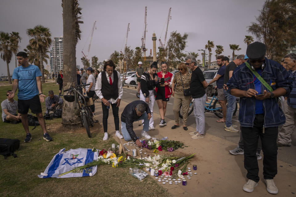 People gather and lay flowers at the site where Alessandro Parini, an Italian tourist, was killed in a Palestinian attack, in Tel Aviv, Israel, Saturday, April 8, 2023. Israeli authorities said an Italian tourist was killed and five other Italian and British citizens were wounded Friday when a car rammed into a group of tourists in Tel Aviv. (AP Photo/Oded Balilty)