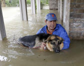 <p>Joe Garcia carries his dog Heidi from his flooded home as he is rescued from rising floodwaters from Tropical Storm Harvey on Aug. 28, 2017, in Spring, Texas. (Photo: David J. Phillip/AP) </p>