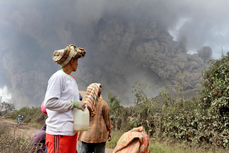 Villagers watch as Mount Sinabung releases pyroclastic flows during an eruption in Namantaran, North Sumatra, Indonesia, Saturday, Feb. 1, 2014. The rumbling volcano in western Indonesia has unleashed fresh clouds of searing gas, killing a number people and injuring few others. (AP Photo)