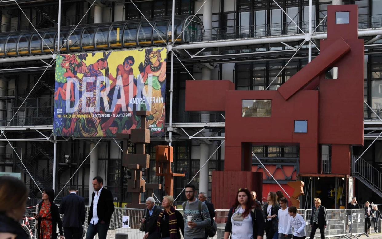 Pedestrians walk in front of the art work by Dutch artist Joep Van Lieshout,