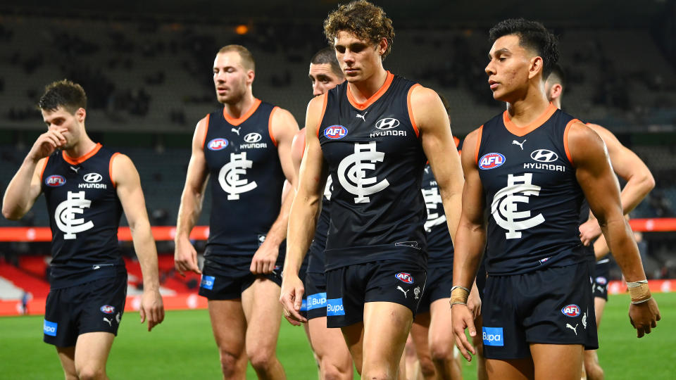 Carlton players walk off the field after their loss to the Lions.