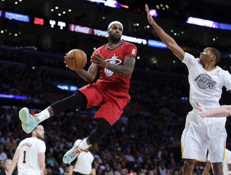 Miami Heat forward LeBron James, left, passes around Los Angeles Lakers guard Wesley Johnson during the second half of an NBA basketball game in Los Angeles, Wednesday, Dec. 25, 2013. (AP Photo/Chris Carlson)